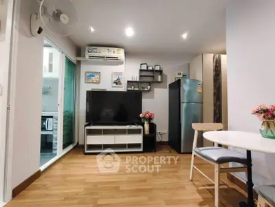 Modern living room with TV, dining area, and kitchen view in stylish apartment.