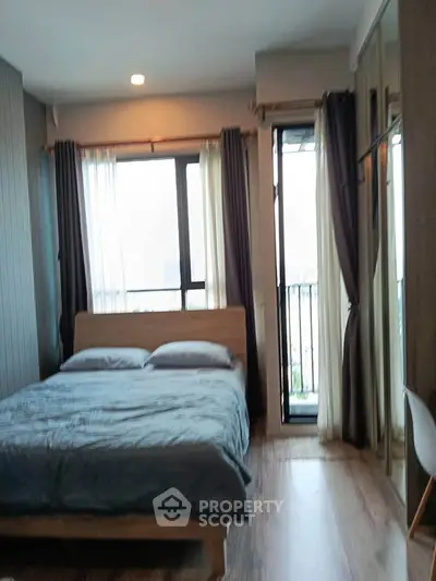 Cozy bedroom with large windows and balcony access in modern apartment.