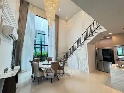Luxurious modern living room with high ceiling, elegant chandelier, and stylish dining area.