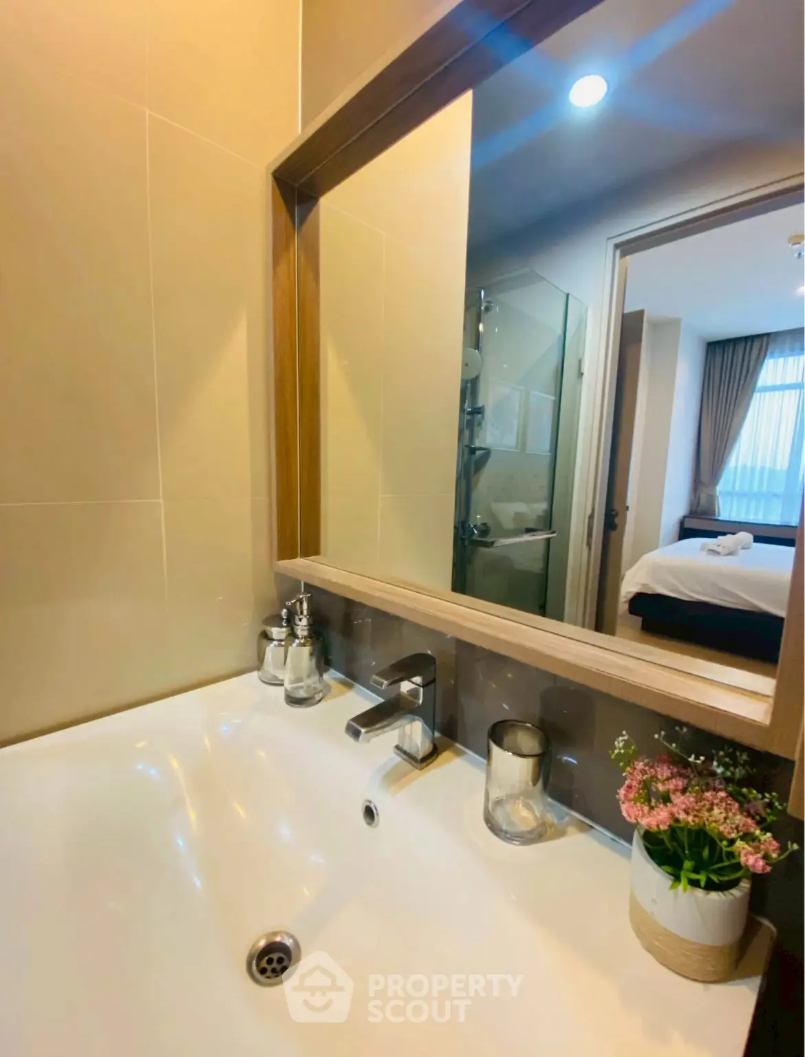 Modern bathroom with sleek sink and mirror reflecting a cozy bedroom view.