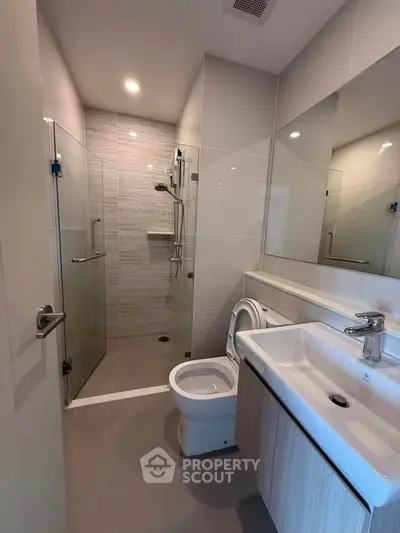 Modern bathroom with glass shower and sleek fixtures in a contemporary apartment.