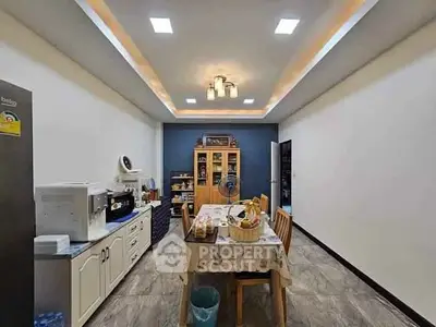 Spacious kitchen with modern lighting and dining area, featuring ample storage and sleek appliances.