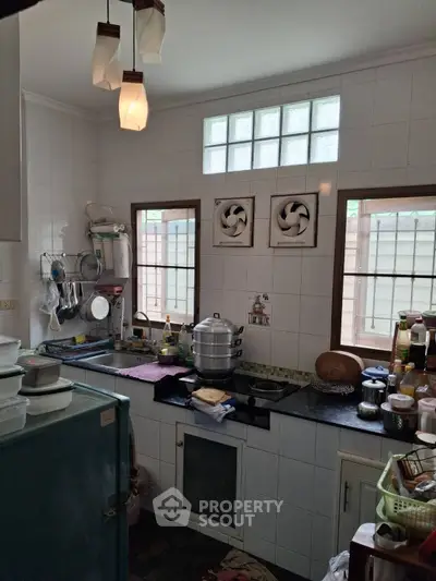 Cozy kitchen with gas stove and ample natural light, perfect for culinary enthusiasts.
