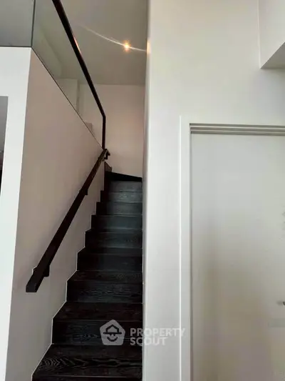 Modern staircase with sleek black steps and glass railing in a contemporary home
