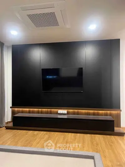 Modern living room with sleek black entertainment wall and wooden flooring