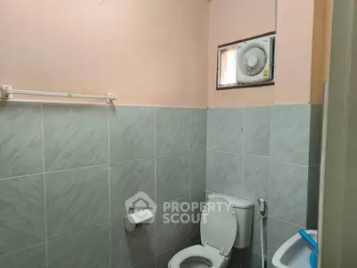 Compact bathroom with tiled walls and essential fixtures, featuring a small window for ventilation.