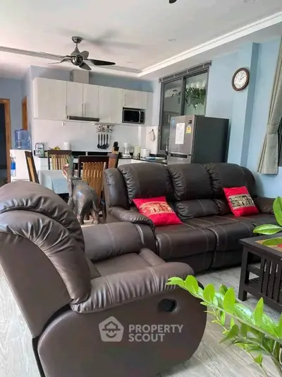 Spacious living room with modern kitchen, leather sofas, and stylish decor in a contemporary apartment.