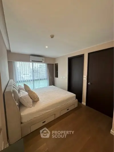 Modern bedroom with large window and stylish decor in a high-rise apartment.
