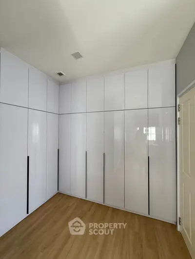 Spacious modern storage room with sleek white cabinets and wooden flooring