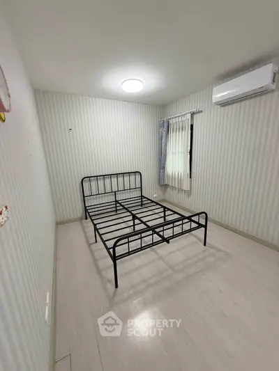 Minimalist bedroom with metal bed frame and air conditioning in modern apartment.