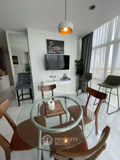 Modern living room with glass table and stylish chairs, featuring large windows and contemporary decor.