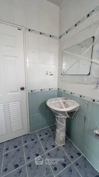 Spacious bathroom with pedestal sink and tiled walls, ready for renovation.