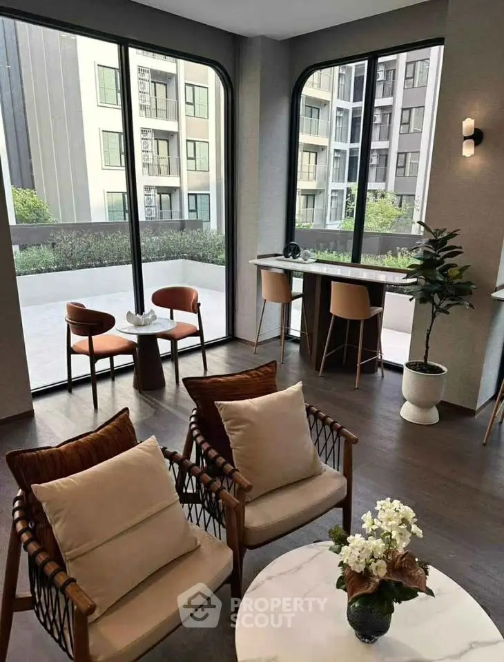 Modern living room with large windows and stylish furniture overlooking a spacious balcony.