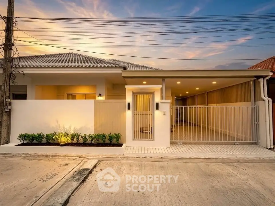 Modern single-story house with gated entrance and driveway at sunset.
