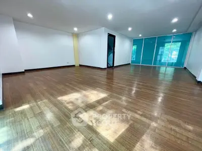 Spacious open-plan living room with wooden flooring and large windows