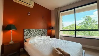 Cozy bedroom with large window offering lush green views, featuring stylish decor and air conditioning.