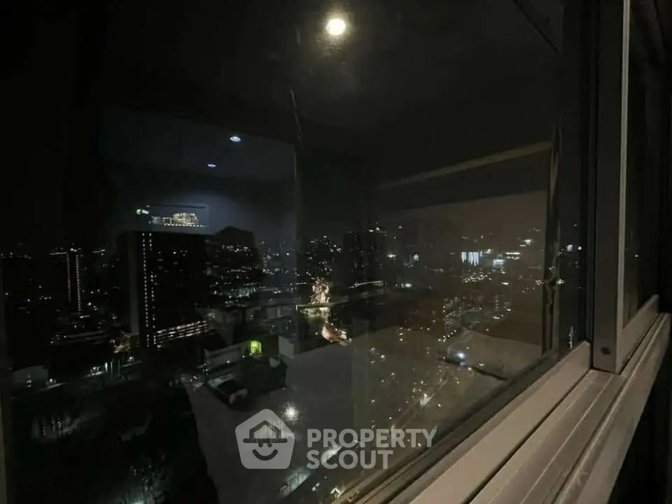 Stunning night cityscape view from a high-rise apartment window, showcasing vibrant urban lights.