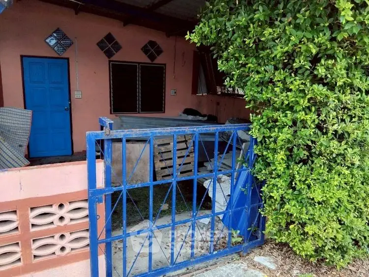 Charming rustic exterior with blue gate and lush greenery