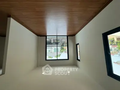 Spacious room with large windows and wooden ceiling, offering ample natural light and modern design.