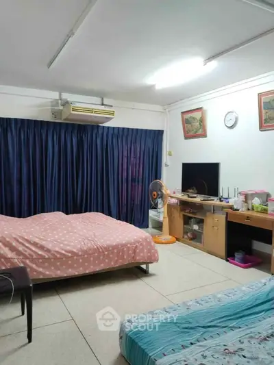 Cozy bedroom with two beds, TV, and air conditioning, perfect for comfortable living.