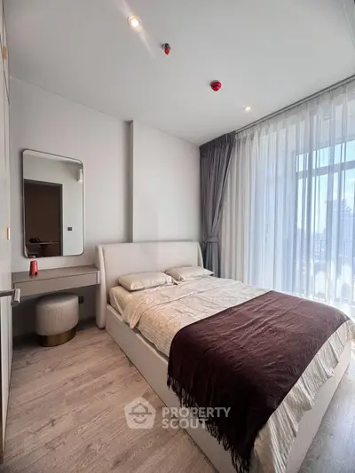 Modern bedroom with large window and elegant decor in a high-rise apartment.