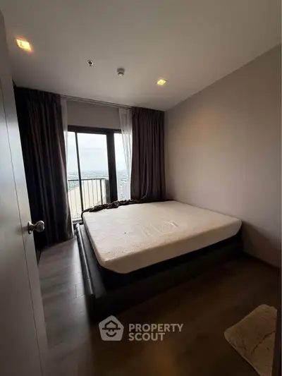 Cozy bedroom with large window offering stunning city view, modern furnishings, and elegant decor.