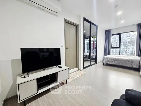 Modern apartment interior with open living room and bedroom, featuring sleek design and natural light.