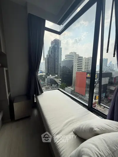 Modern bedroom with large window offering stunning city view in high-rise apartment.