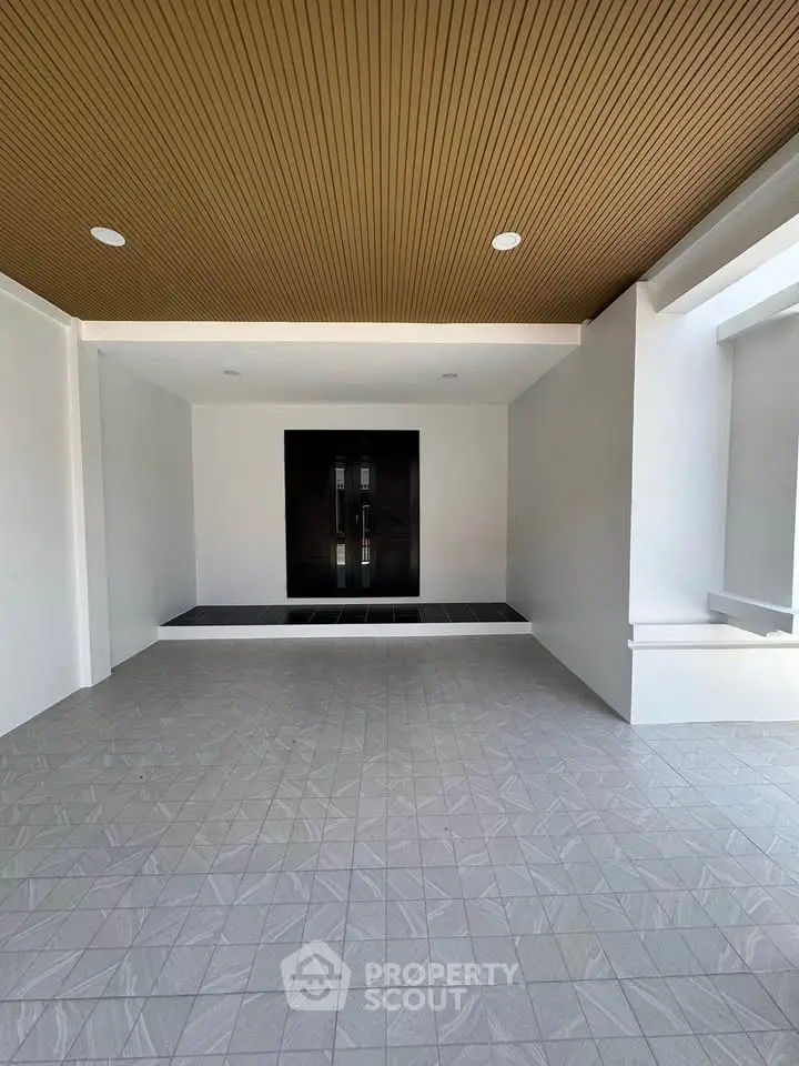 Modern entrance with sleek design and elegant double doors, featuring a stylish ceiling and tiled flooring.