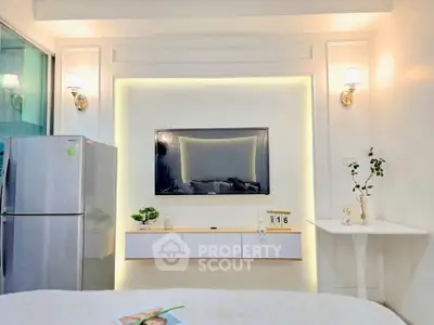 Modern living room with sleek TV setup and stainless steel fridge, perfect for contemporary living.