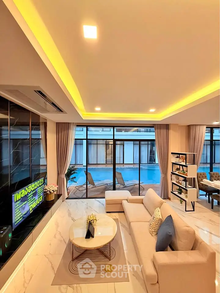 Luxurious modern living room with pool view, elegant decor, and ambient lighting.