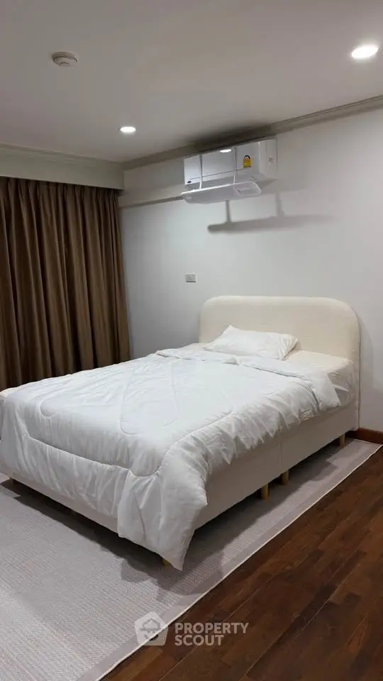 Cozy bedroom with modern air conditioning and elegant wooden flooring, perfect for restful nights.