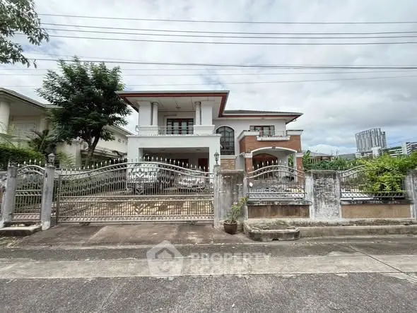 Elegant two-story house with gated entrance and spacious driveway in a suburban neighborhood.