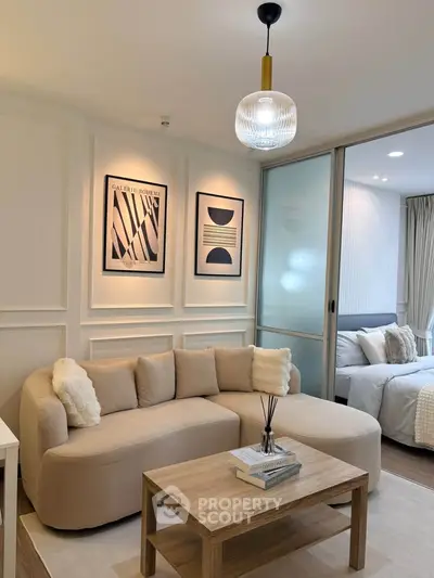 Modern living room with cozy beige sofa and stylish decor adjacent to a bedroom.