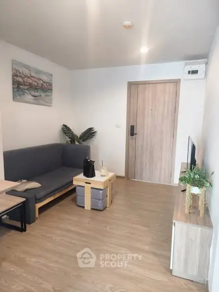 Modern living room with wooden flooring, cozy sofa, and stylish decor in a contemporary apartment.