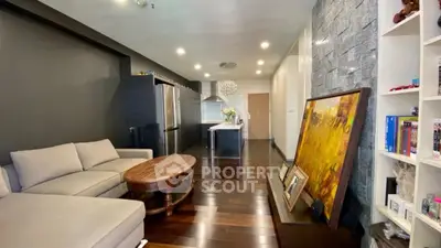Modern living room with open kitchen, dark wood floors, and stylish decor