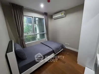 Cozy bedroom with single bed, air conditioning, and large window for natural light.