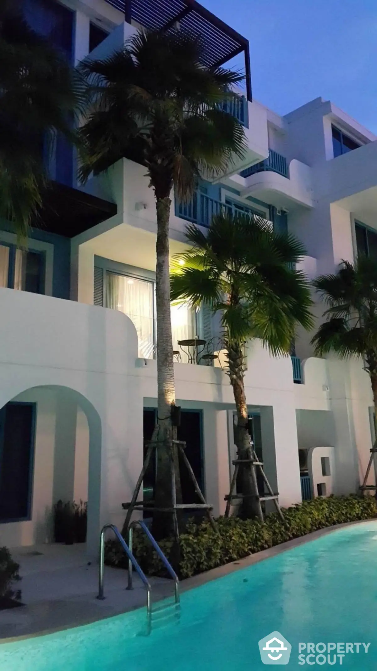 Luxurious modern apartment with poolside view and palm trees at dusk