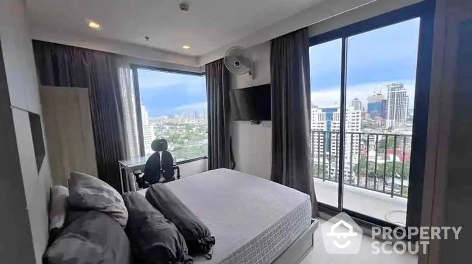 Modern bedroom with city view and balcony access in high-rise apartment