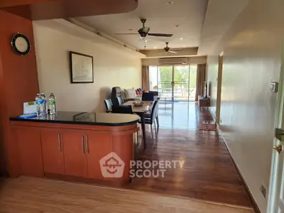 Spacious open-plan living and dining area with wooden flooring and balcony view.