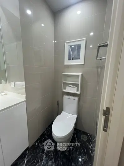 Modern bathroom with sleek design and marble flooring, featuring a toilet and stylish wall tiles.