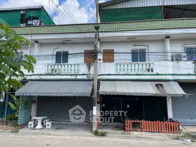 Charming two-story commercial building with green roof and street view, ideal for business opportunities.
