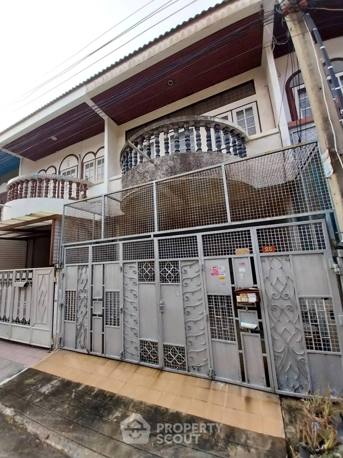 Charming townhouse with intricate metal gate and balcony in urban setting.