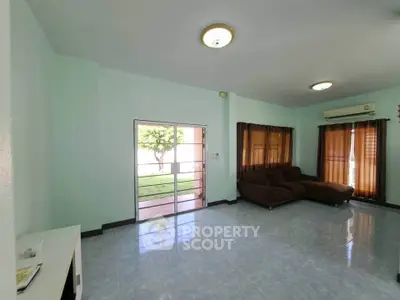 Spacious living room with large windows and garden view, featuring a cozy brown sofa and air conditioning.