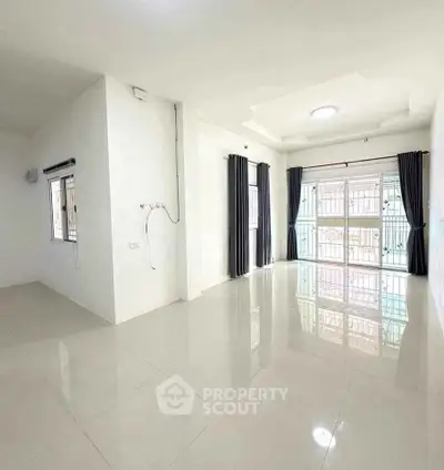 Spacious and bright living room with large windows and elegant curtains.