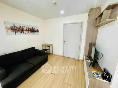 Modern living room with sleek black sofa and wall-mounted TV in a cozy apartment.
