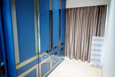 Spacious bedroom with sleek blue wardrobes and elegant curtains