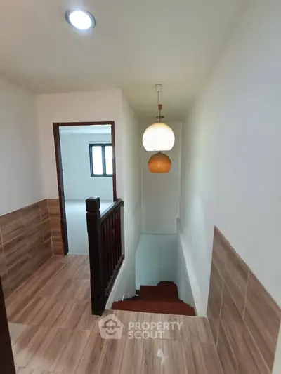 Charming hallway with modern lighting and wooden staircase in a cozy home