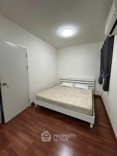 Cozy bedroom with wooden flooring and modern bed frame, ideal for restful nights.