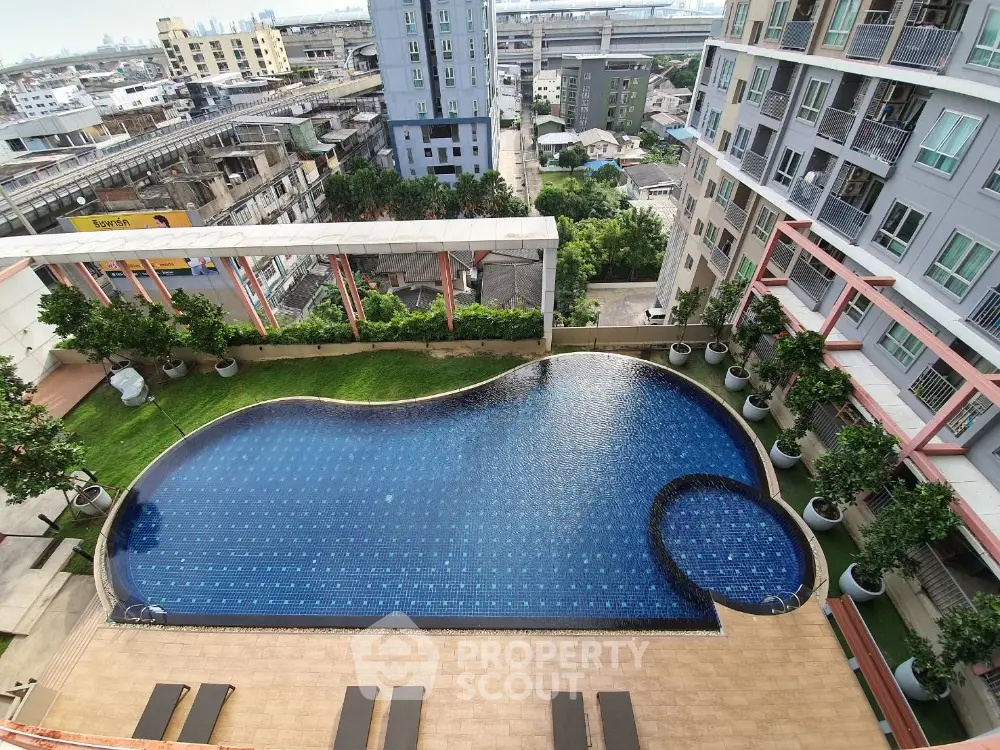 Stunning aerial view of modern apartment complex with luxurious swimming pool and cityscape backdrop.